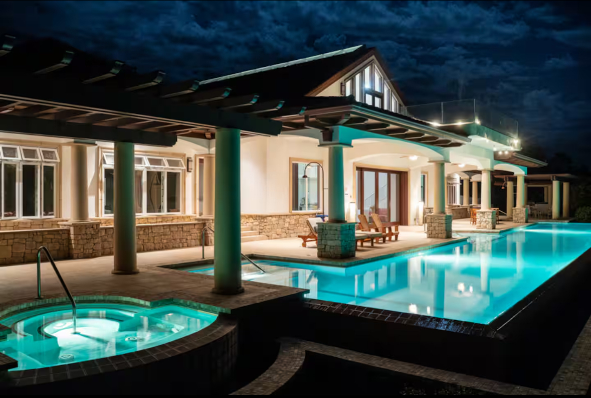The retreat center illuminated at night with the pool glowing blue