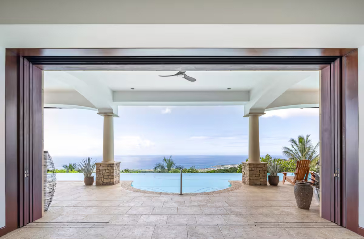 View through the open living room toward the infinity pool and ocean horizon