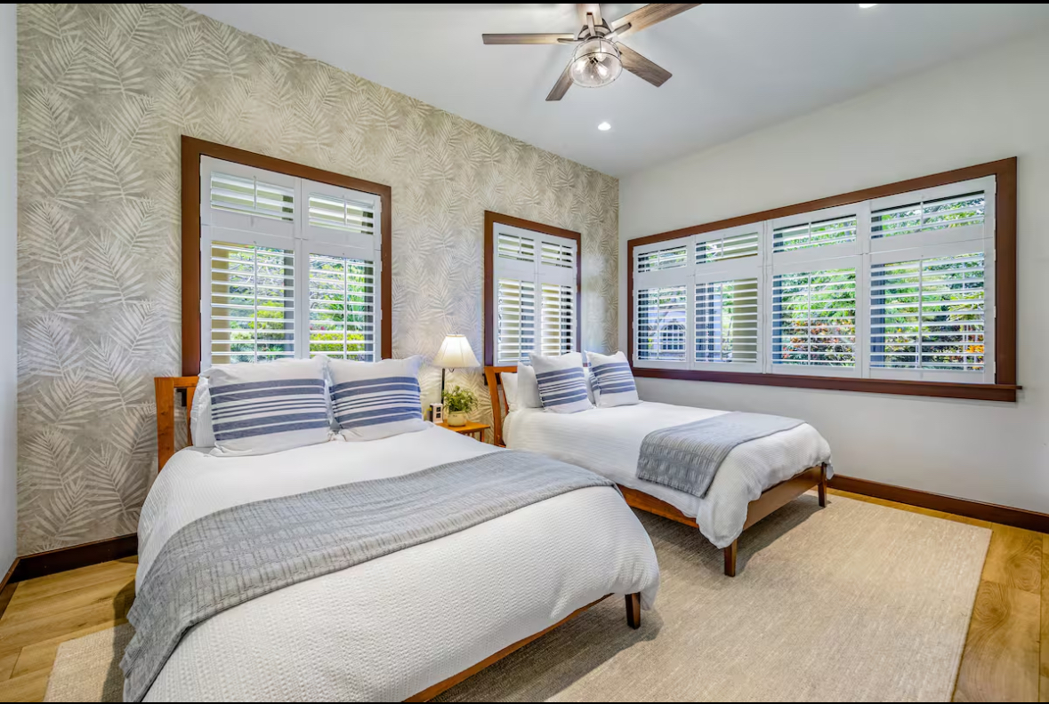 Bedroom with two beds, wallpaper detail, and large windows