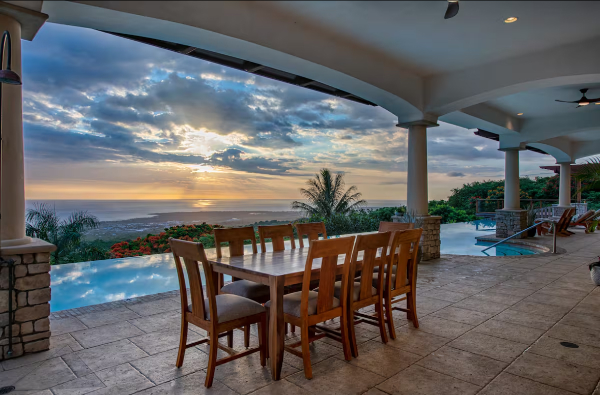 Outdoor dining area beside the infinity pool at sunset