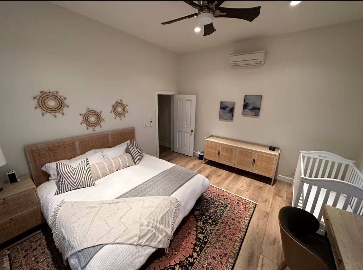 King bedroom with a crib, woven furnishings, and a patterned rug