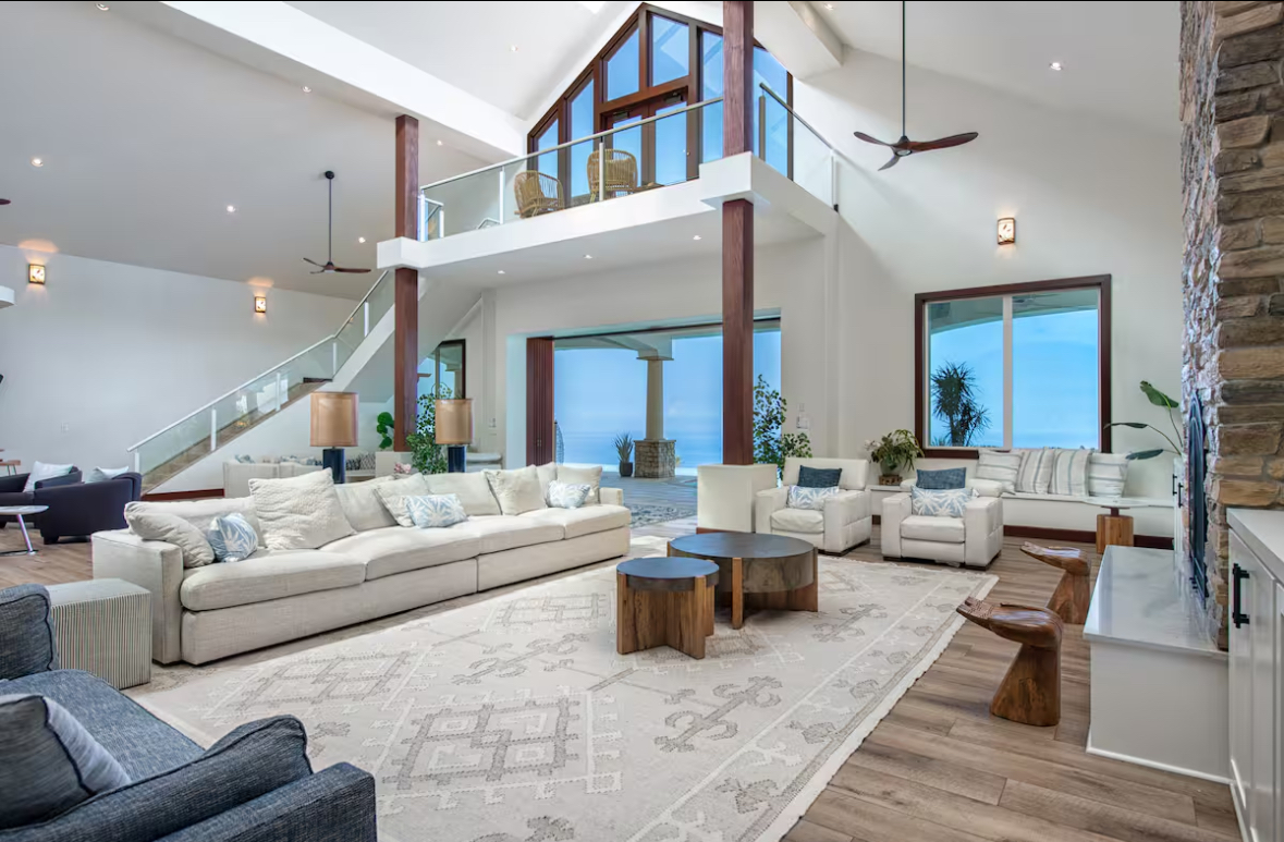 Ocean-view lounge with large sofa seating and an open mezzanine above