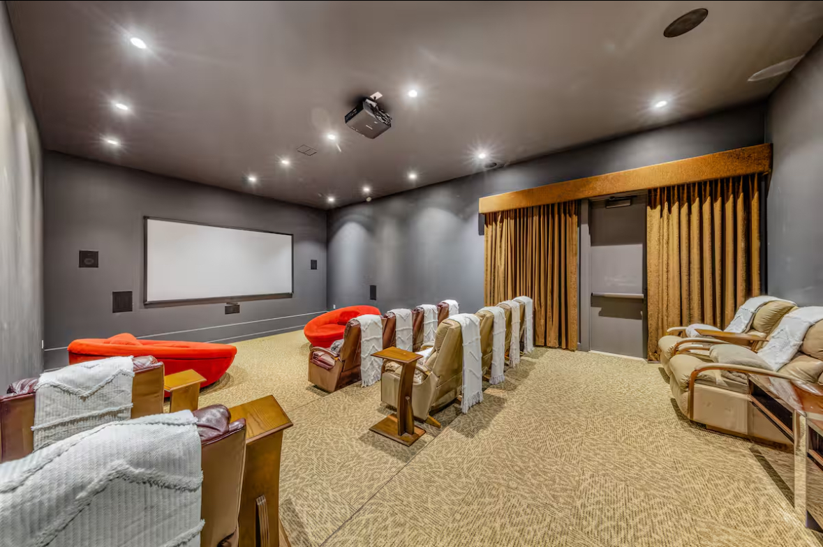 Private home theater with tiered recliners, plush seating, and a projection screen